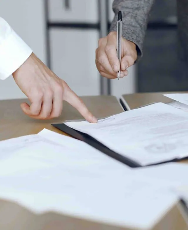 Mains signant un document sur un bureau